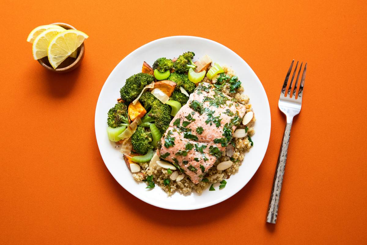 Sheet pan portion with evenly spaced frozen chicken breasts and broccoli florets ready for roasting